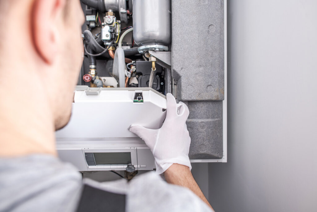 Close-up of a technician fixing a central heating furnace system.